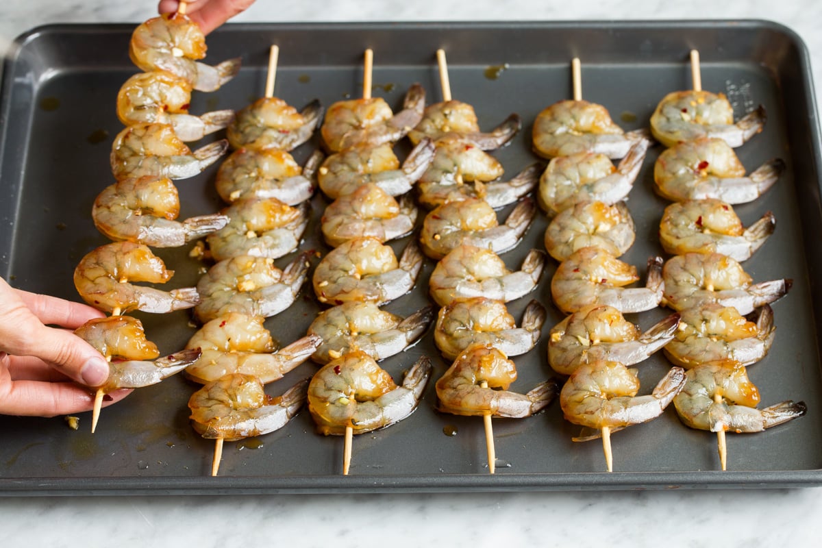 Grilled Shrimp with Honey Garlic Marinade - only 4 ingredients in this fast, easy and flavorful marinade! Perfect for a quick dinner! #shrimp #marinade #grilledshrimp #dinner #recipe Showing how to thread shrimp onto wooden skewers.