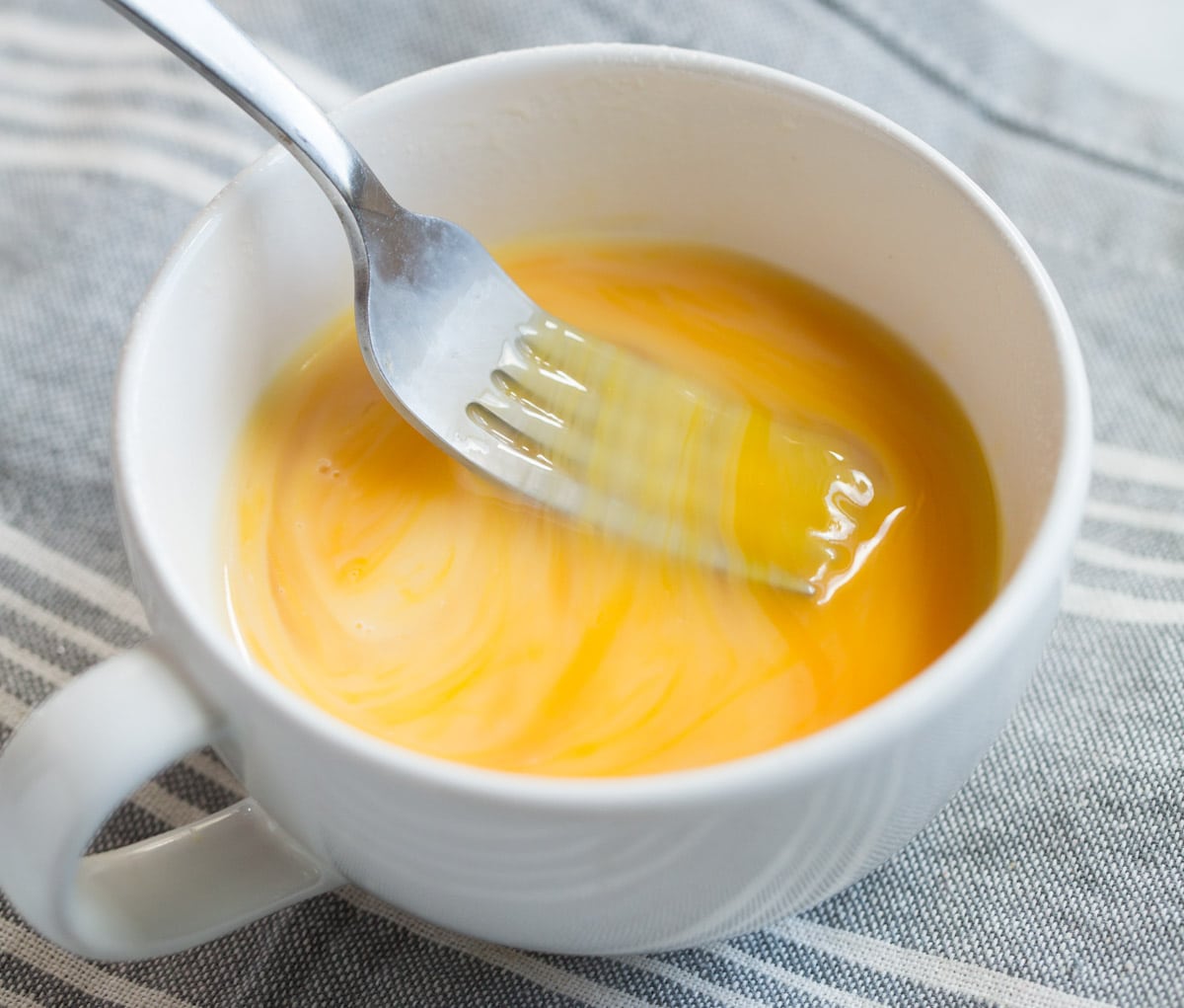 Stir to blend with a fork (be sure to break egg yolk or it can burst). Mixing eggs and milk in mug with a fork