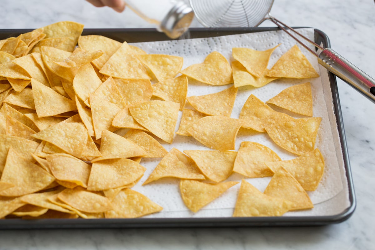 Homemade Tortilla Chips Draining fried tortilla chips on a baking sheet lined with paper towels.