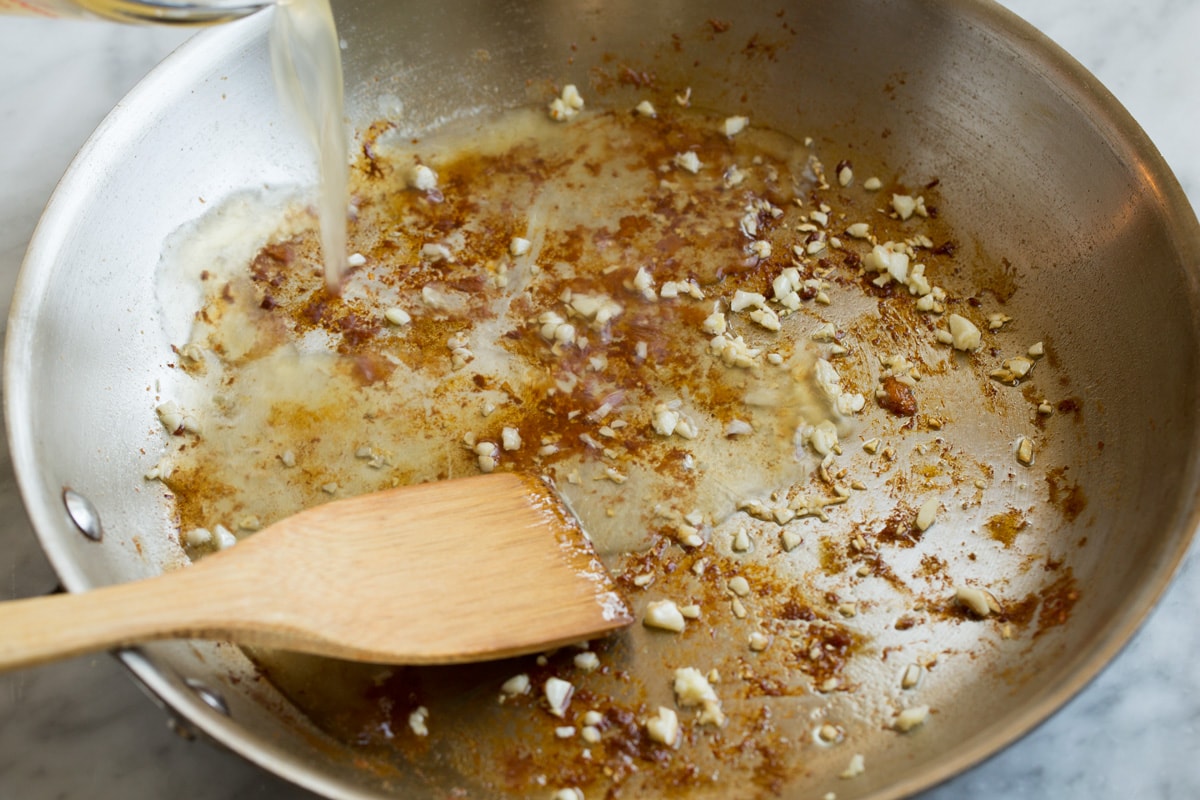 Chicken Piccata Adding chicken broth and lemon to arlic and browned bits in the bottom of a skillet.