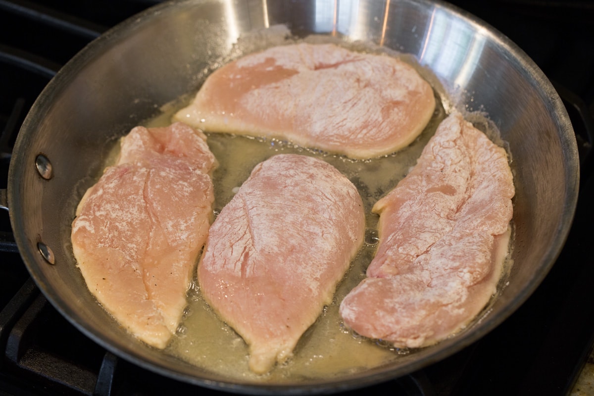 Chicken Piccata Pan searing four chicken pieces.