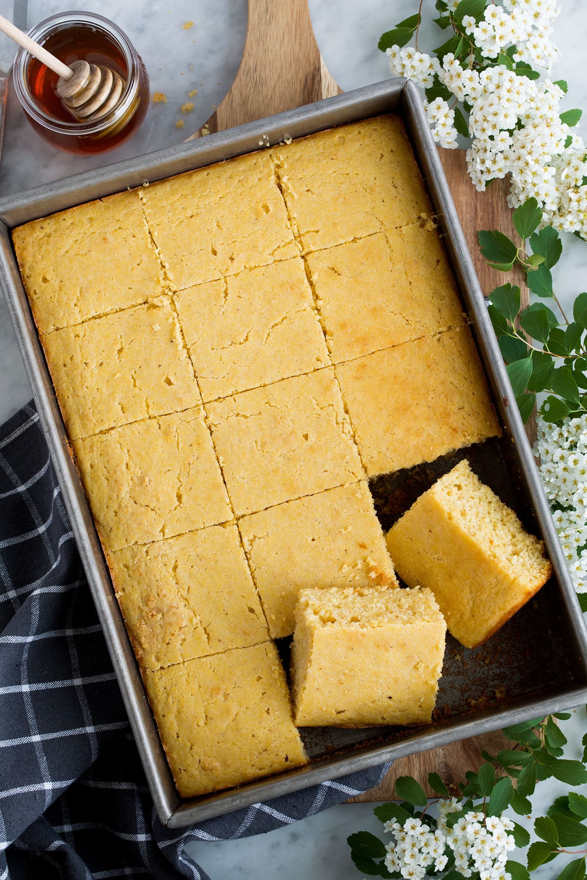 The BEST Cornbread! Soft, moist, tender and perfectly delicious! The only cornbread recipe you'll ever need! #cornbread #bread #sidedish #thanksgiving #recipe Overhead image of cornbread cut into squares in a baking dish.