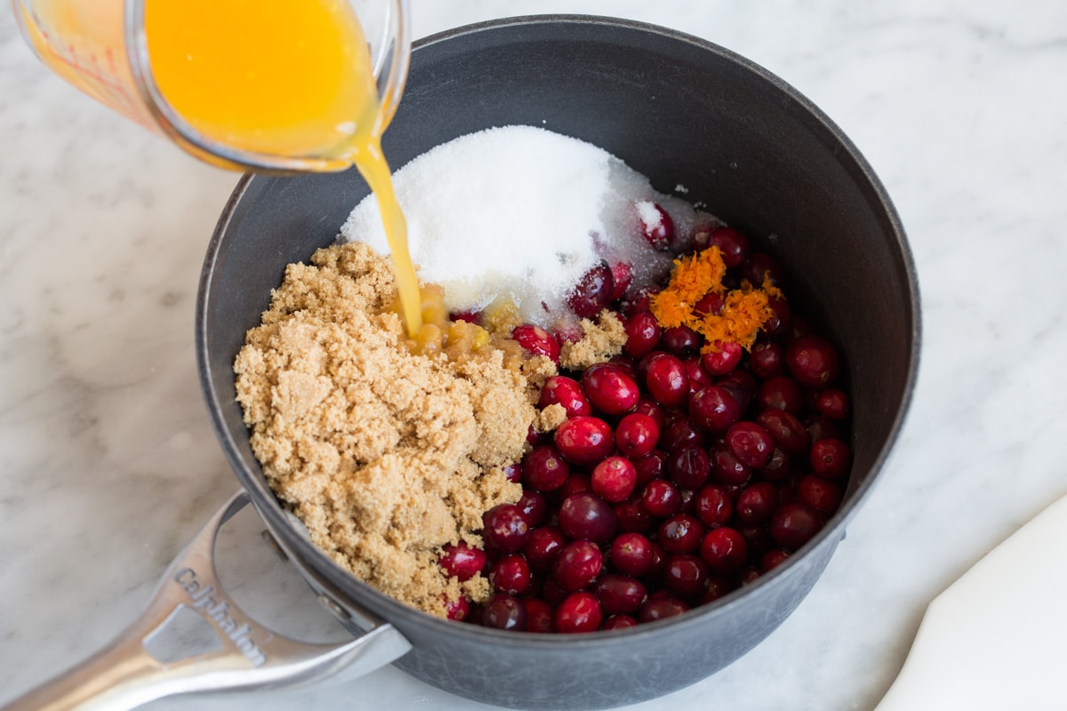 Fresh Cranberry Sauce Recipe Adding cranberry sauce ingredients to a medium saucepan.