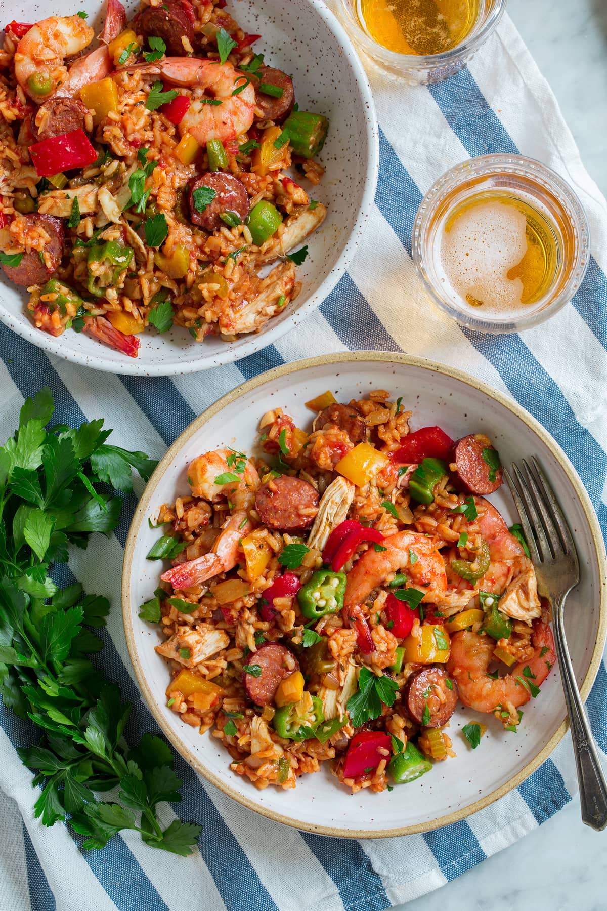 Jambalaya - super hearty and flavorful! Made with sausage, shrimp, chicken, rice, lots of vegetables and a delicious seasoning blend! Love that it's made in one pan. #jambalaya #cajun #southern #recipe Two servings of jambalaya in bowls.