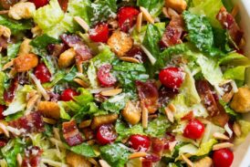 The Best Salad in a large salad bowl. Salad includes romaine lettuce, bacon, croutons, parmesan, swiss cheese, almonds, grape tomatoes and lemon vinaigrette dressing.