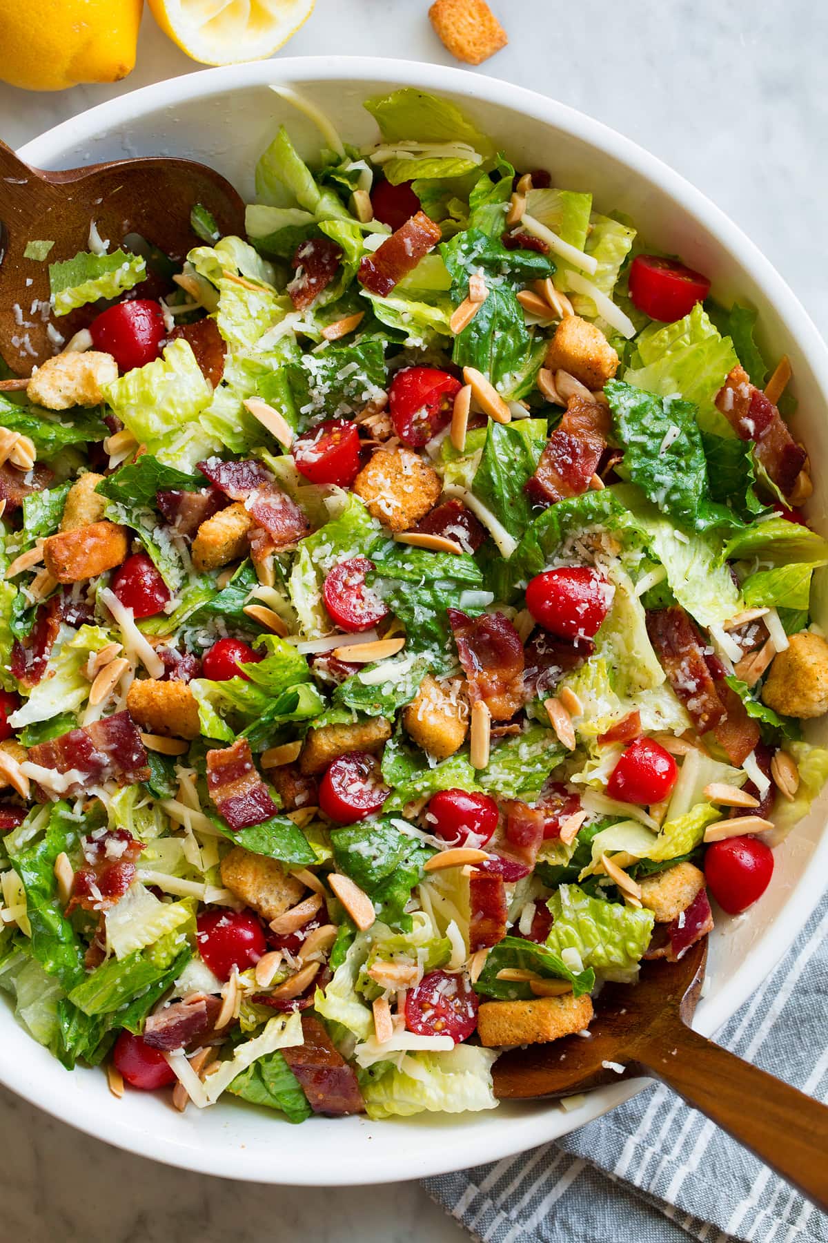 The BEST Salad Recipe {Salad de Maison} The Best Family Favorite Salad in a large salad bowl. Salad includes romaine lettuce, bacon, croutons, parmesan, swiss cheese, almonds, grape tomatoes and lemon vinaigrette dressing.