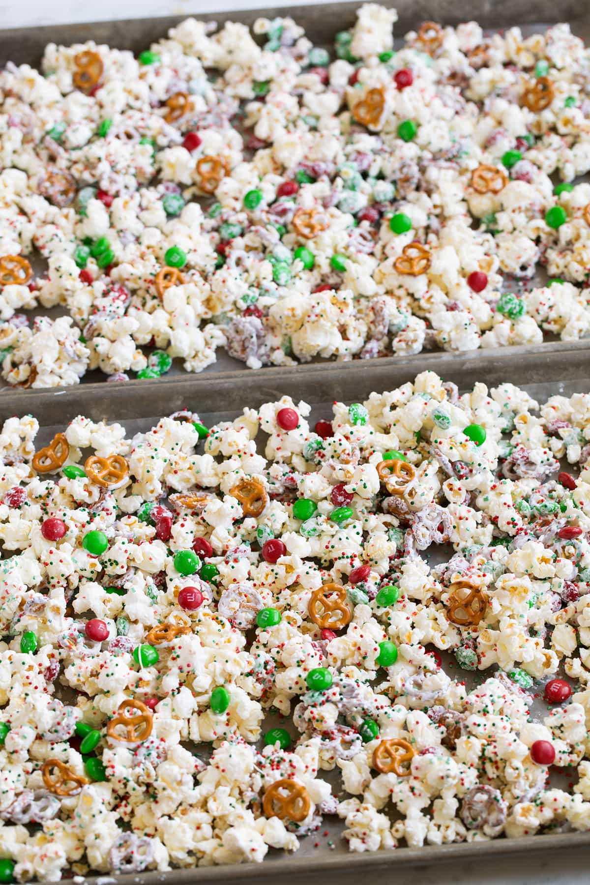 Christmas Crunch Christmas popcorn treat setting in baking sheets over parchment paper to dry.