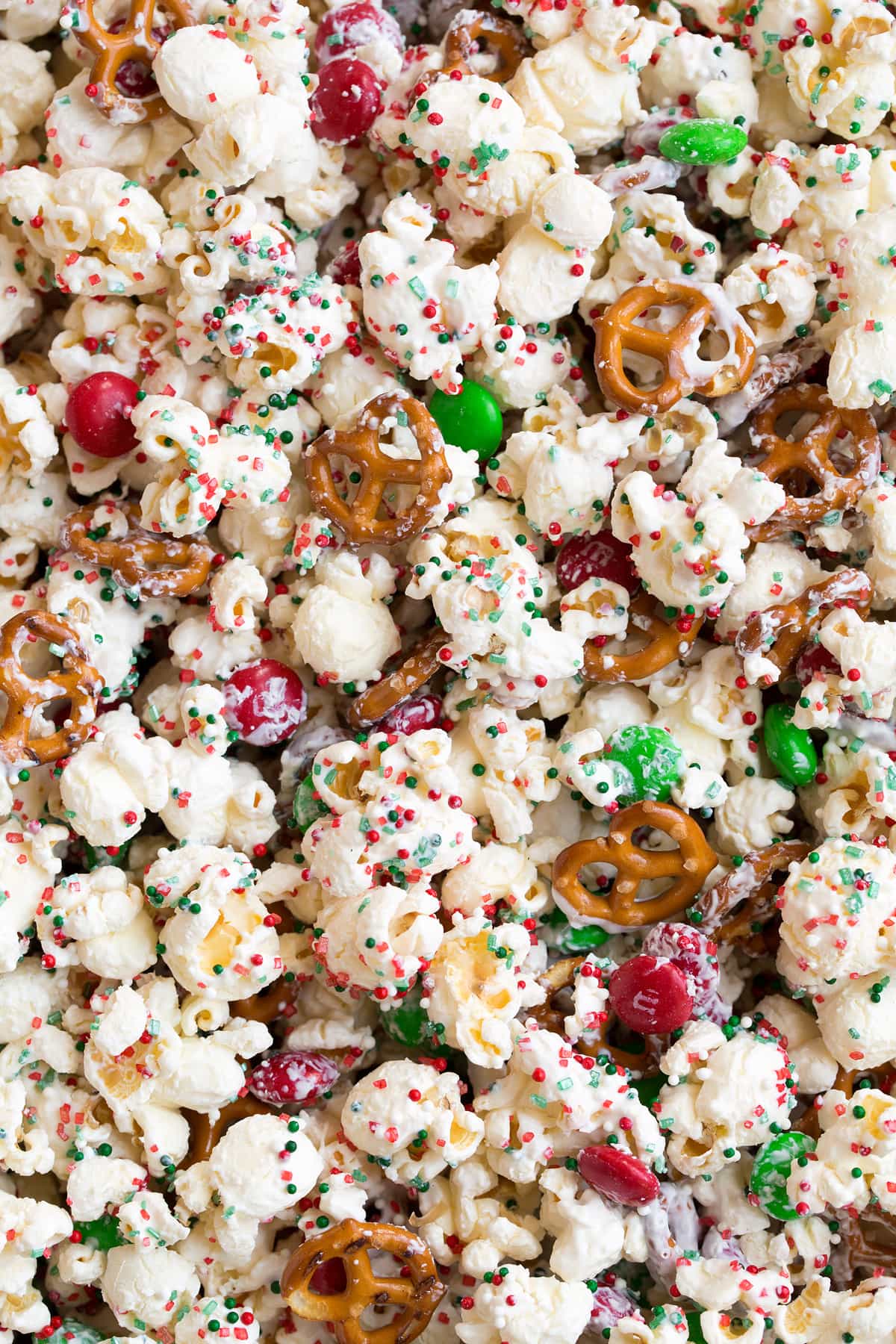 Christmas Crunch Close up image of white chocolate coated popcorn with pretzels sprinkles and m and m's.