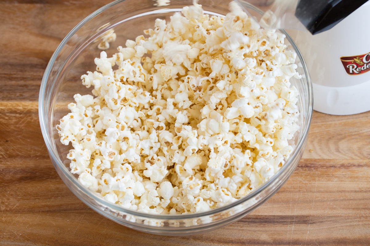 Christmas Crunch Popping popcorn into a glass bowl using an electric popcorn machine.