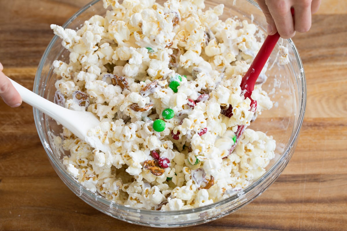 Christmas Crunch Tossing popcorn with melted white chocolate candy melts.