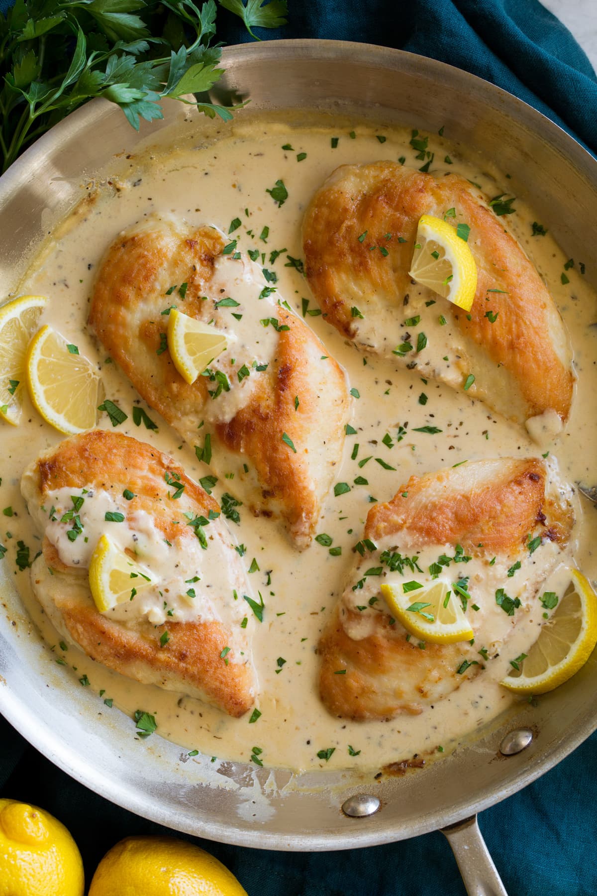 Creamy Lemon Romano Chicken Four pan seared chicken breasts in a skillet with lemon romano sauce.