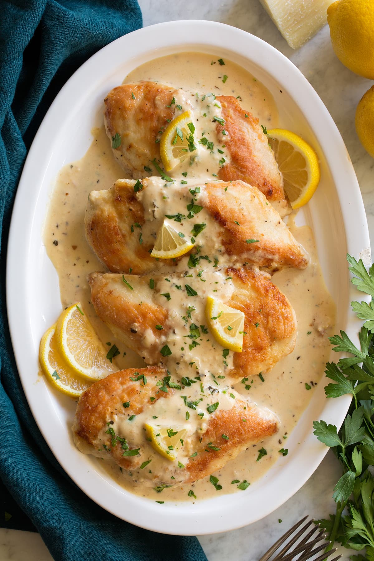 Creamy Lemon Romano Chicken Platter of four pan seared chicken breasts with creamy lemon romano sauce on top.