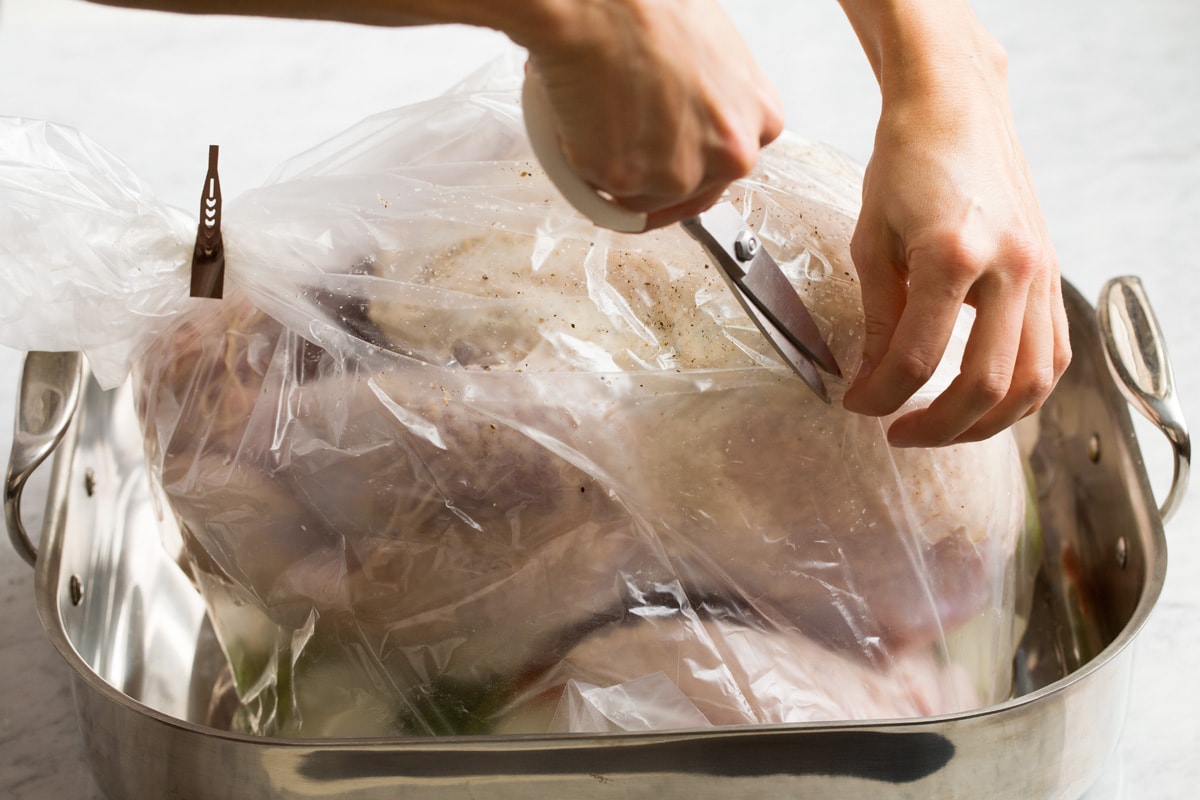 How to Cook Turkey {in an Oven Bag} Cutting slits in an oven bag with a large turkey inside.