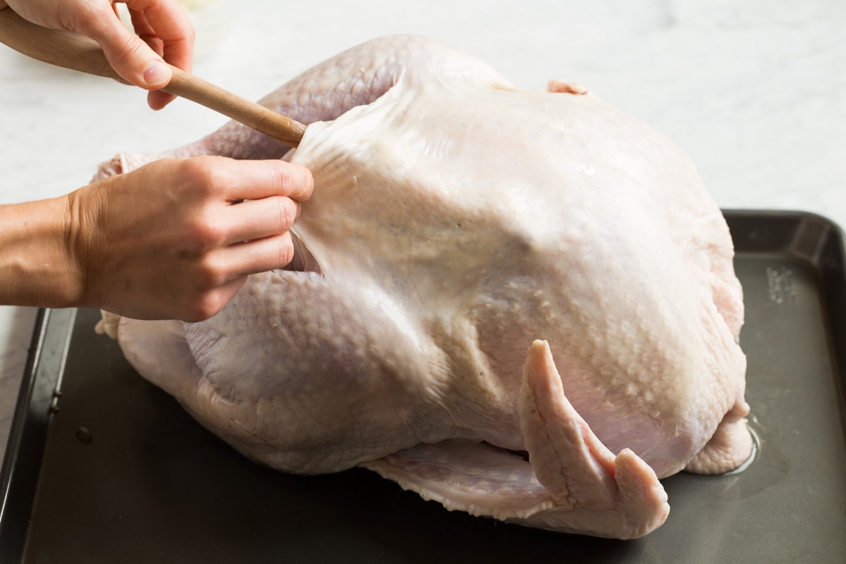 How to Cook Turkey {in an Oven Bag} Separating turkey skin from breast using the back end of a wooden spoon.