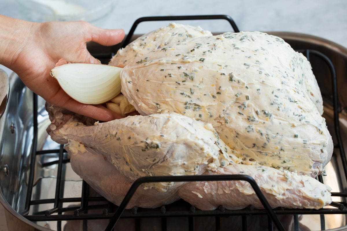 Roast Turkey - easy to follow recipe that turns out tender, juicy and full of flavor! A holiday staple! #turkey #thanksigiving Stuffing turkey with quartered onion and smashed garlic.