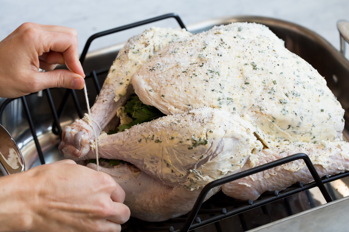 Roast Turkey - easy to follow recipe that turns out tender, juicy and full of flavor! A holiday staple! #turkey #thanksigiving Trussing turkey with kitchen twine.