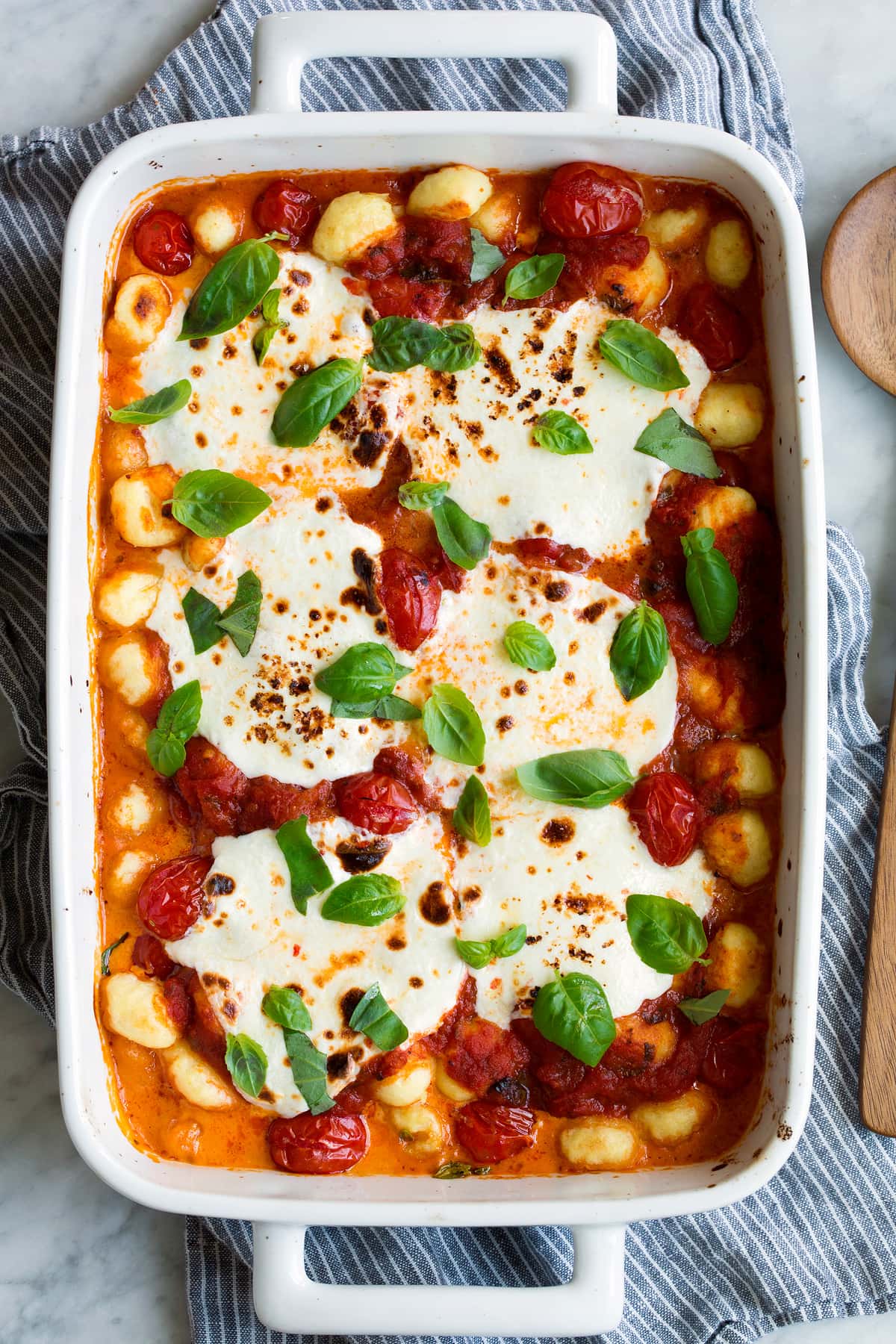 Baked Gnocchi Baked Gnocchi in a white baking dish with marinara sauce, mozzarella and basil.
