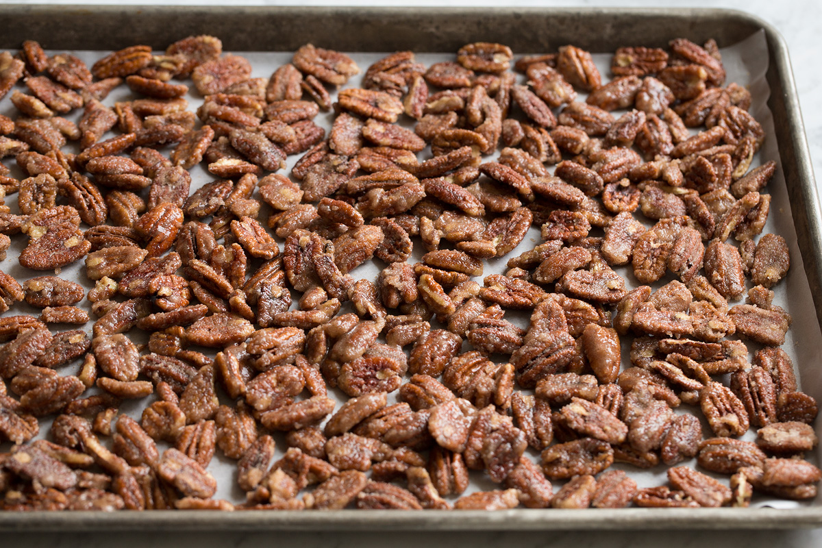 Candied Pecans Pecans coated with sugar spread out on a baking sheet.