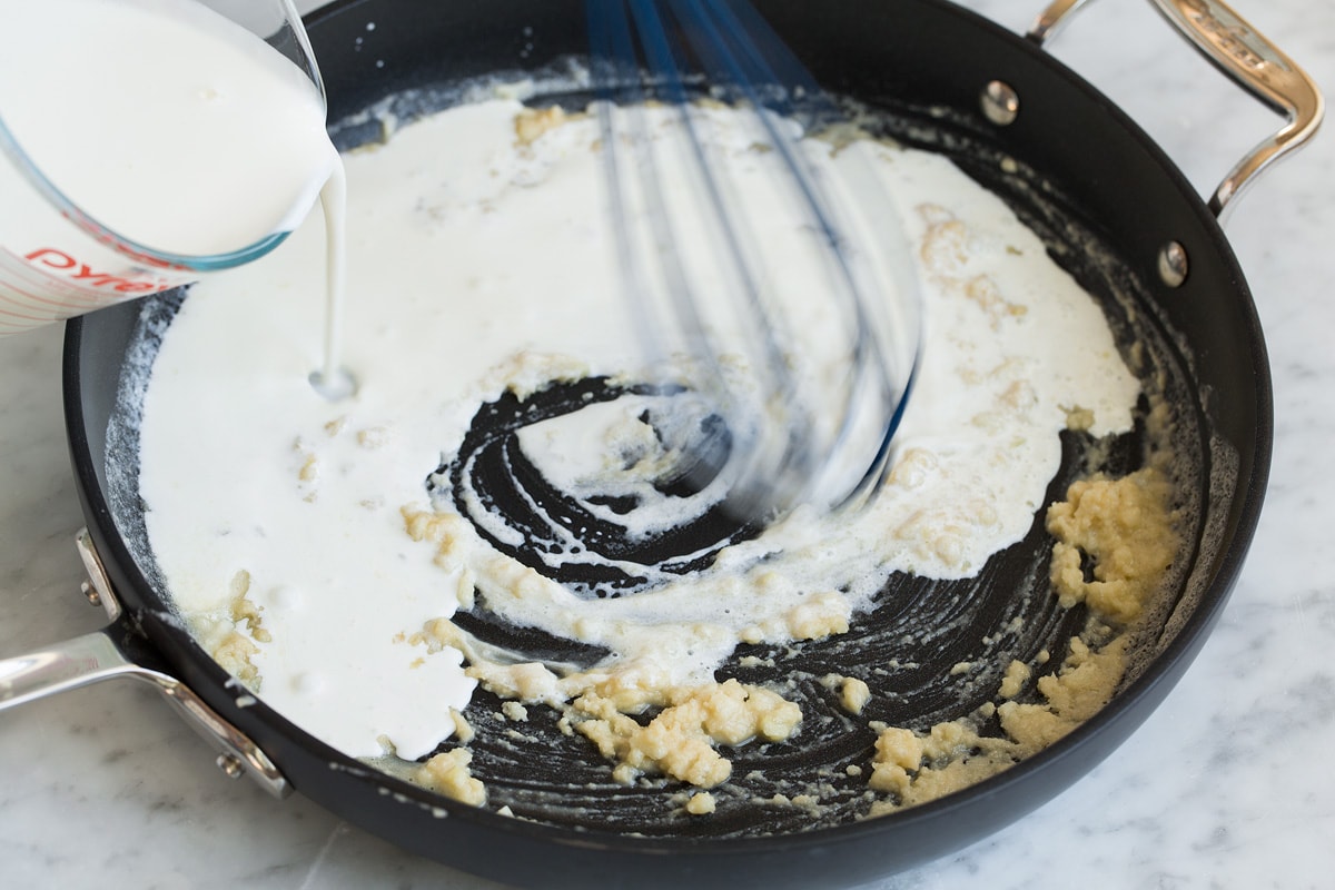 Creamy Spinach Tomato Tortellini Whisking milk to roux in skillet.