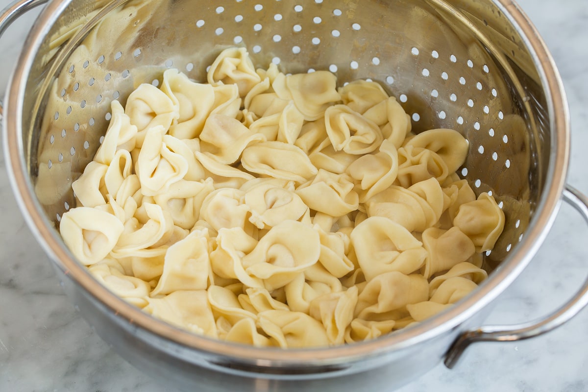 Creamy Spinach Tomato Tortellini Tortellini draining in a colander.