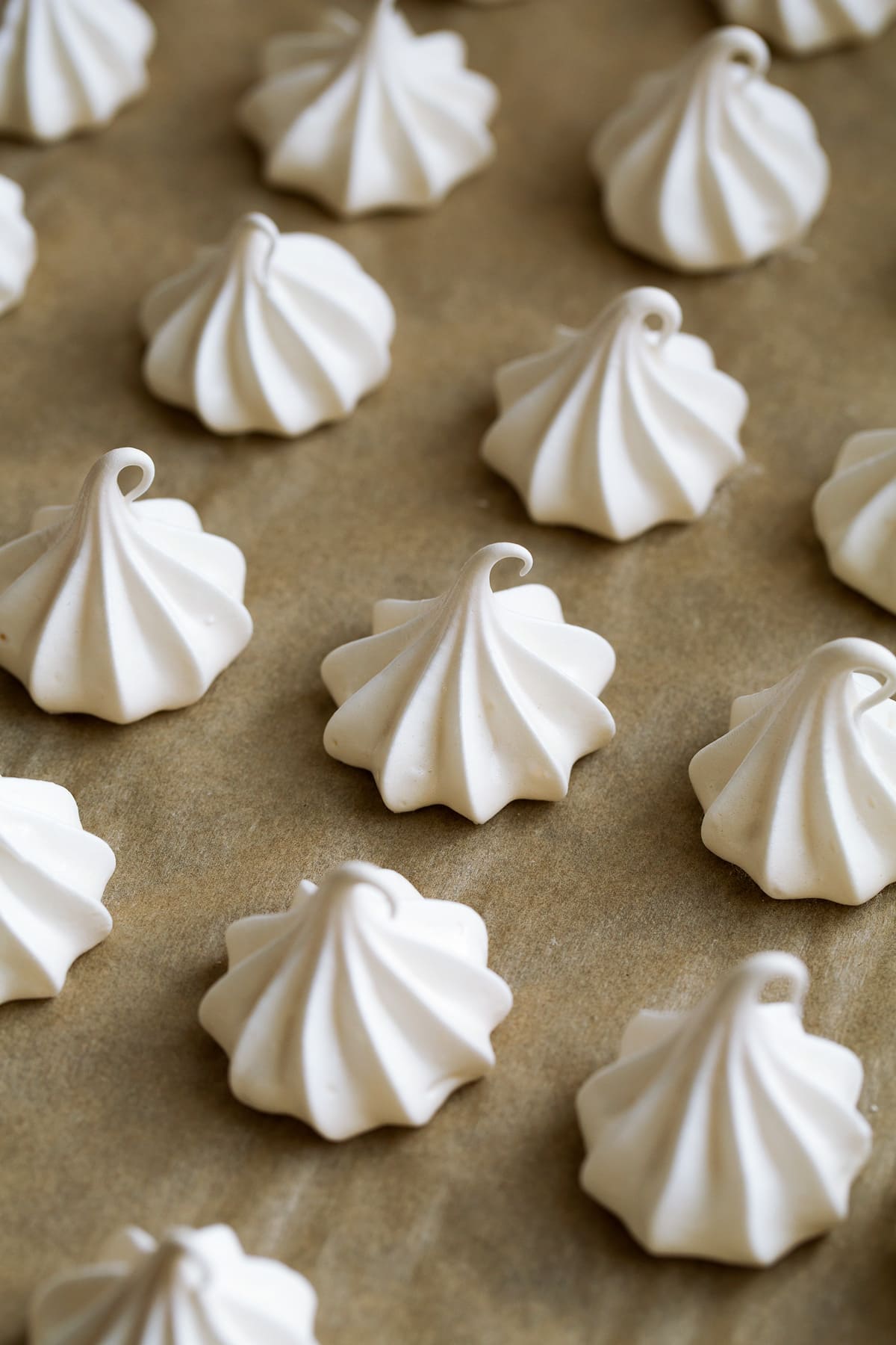 Meringue cookies on parchment paper on baking sheet shown after baking.