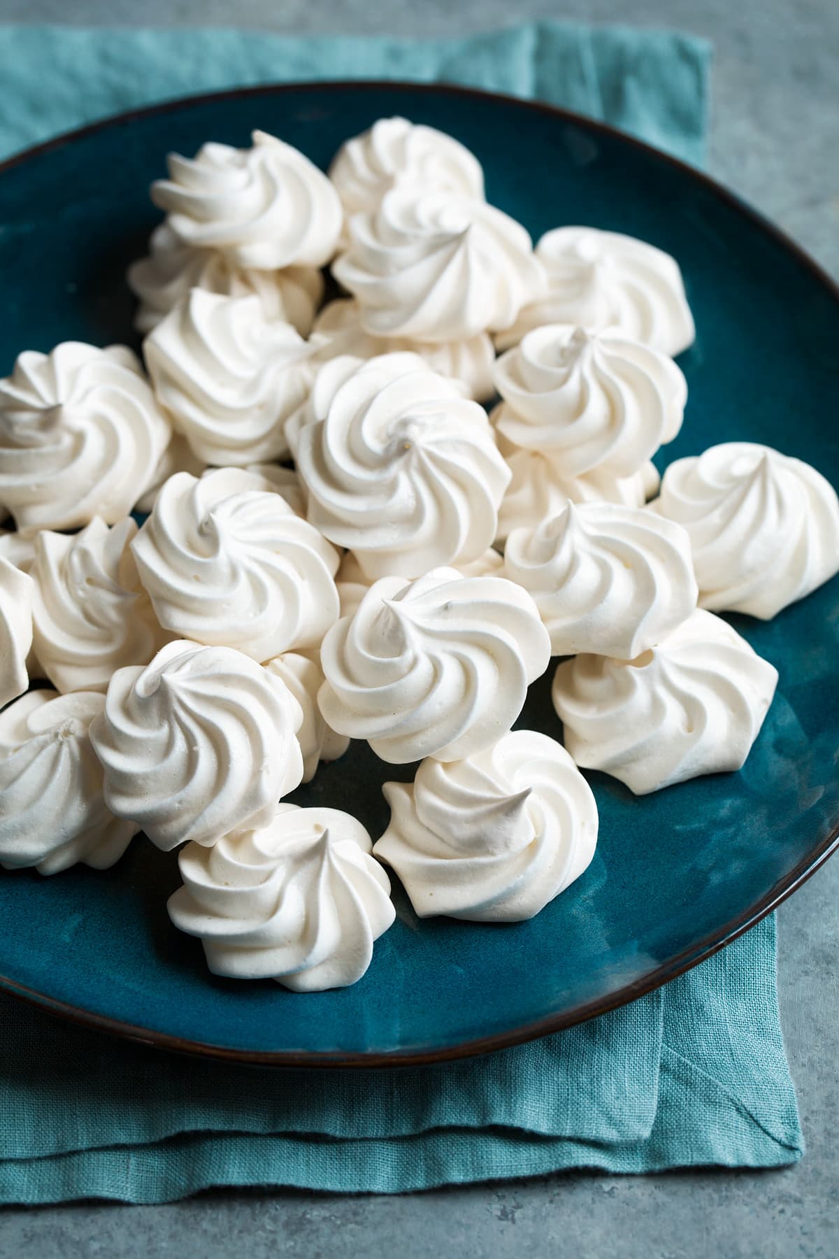 Meringue Cookies Round and swirly white meringue cookies on a large blue plate.