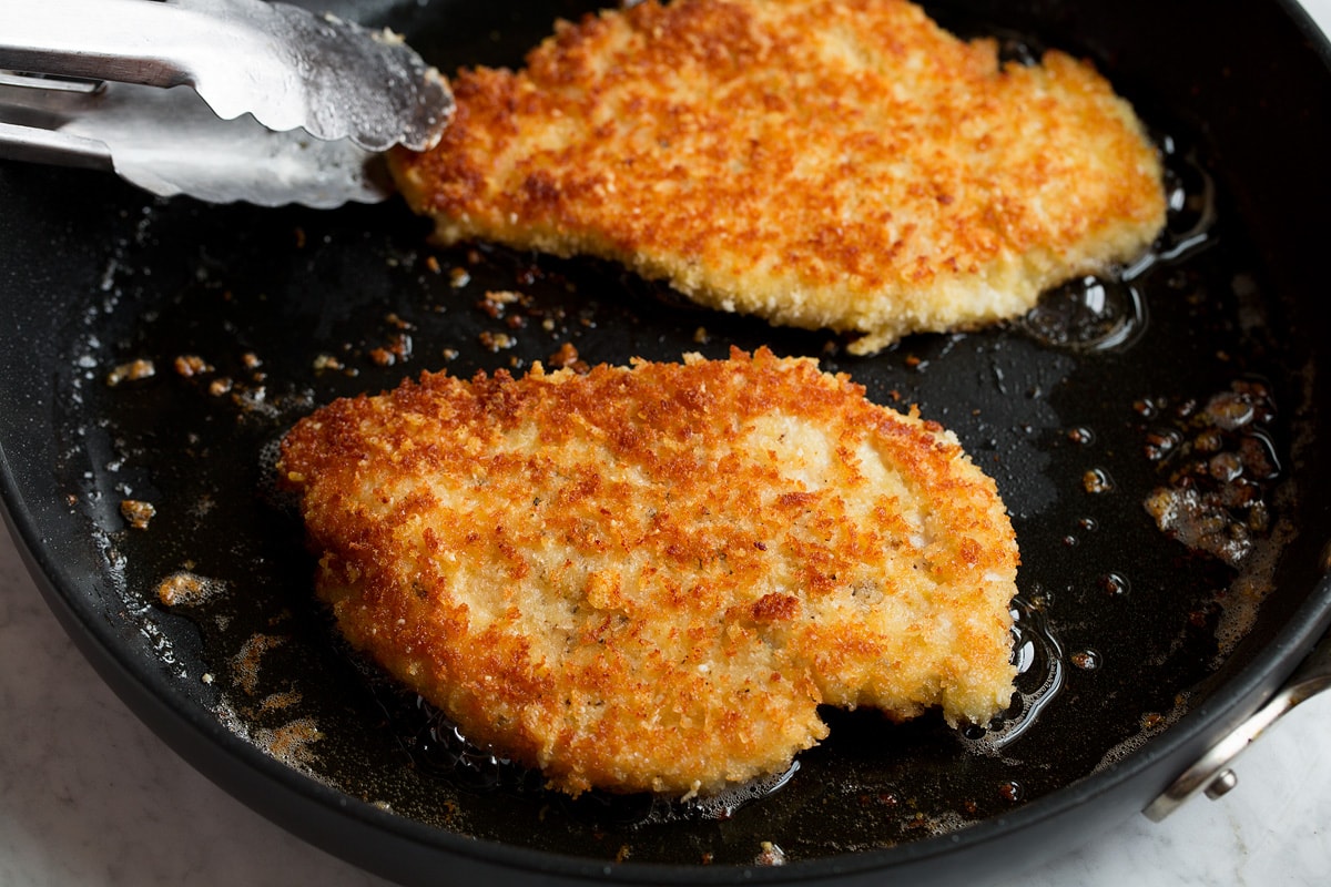 Parmesan Crusted Chicken Parmesan chicken shown being fried in a skillet.