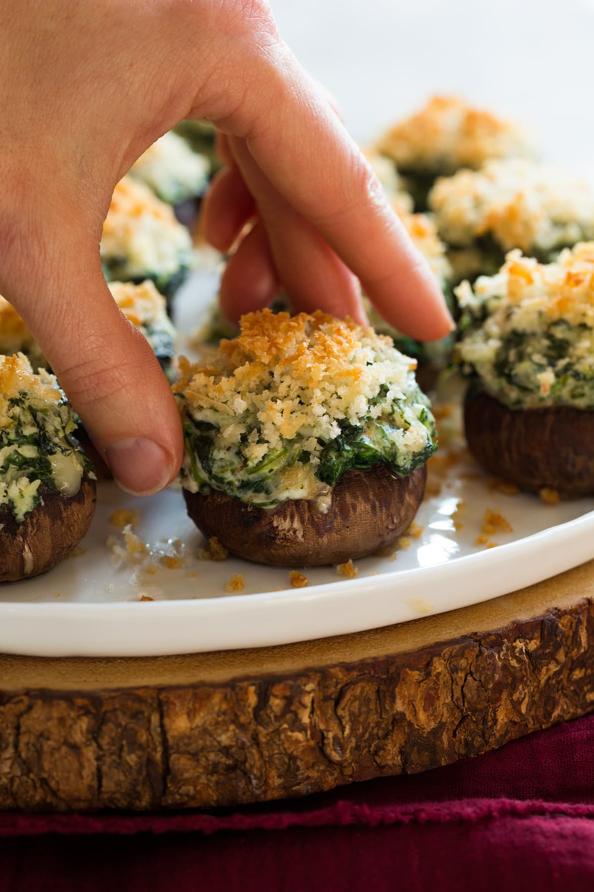 Stuffed Mushrooms Hand picking up a stuffed mushrooms filled with cream cheese, shredded cheeses and spinach.