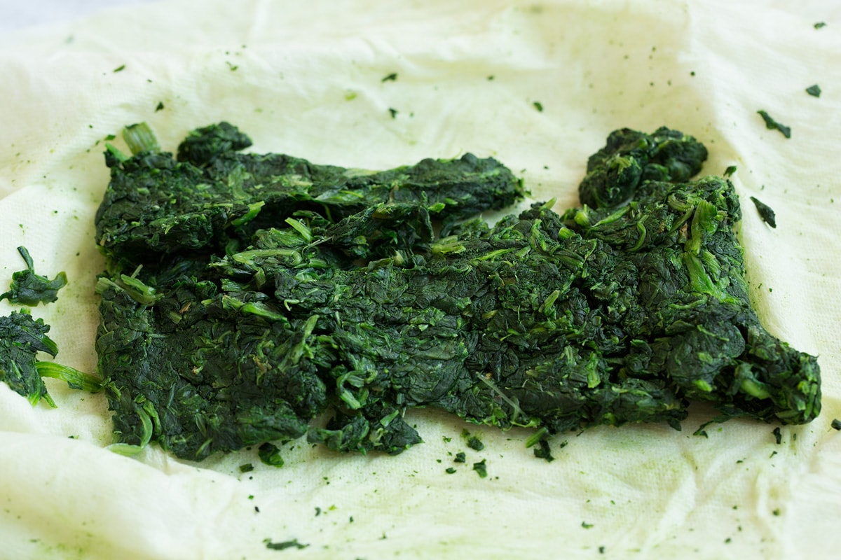 Stuffed Mushrooms Spinach on paper towels shown after squeezing out the excess moisture. The first step to make stuffed mushrooms.