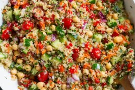 Quinoa Salad in a large serving bowl with wooden tongs on the side.