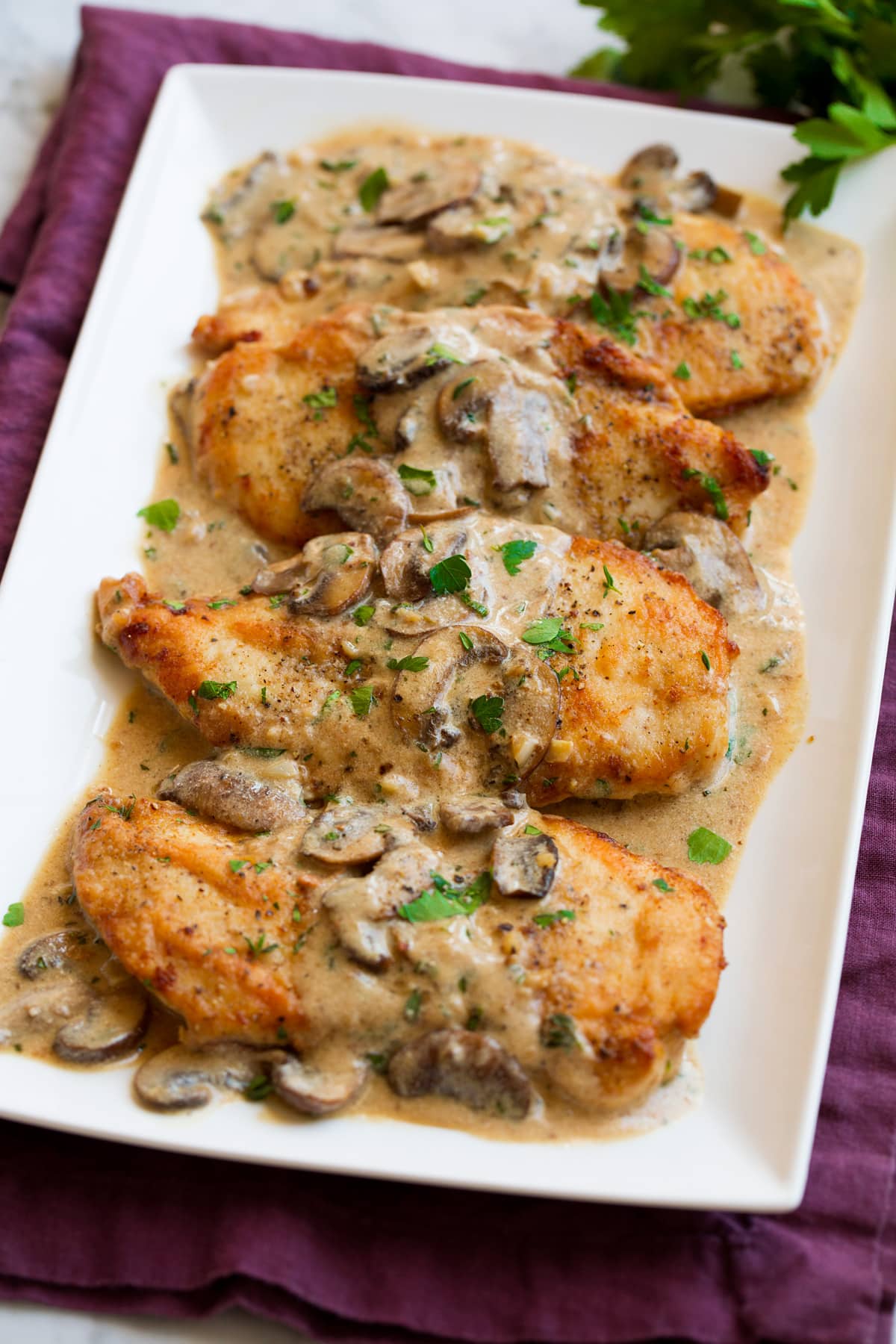 Creamy Chicken Marsala Chicken marsala on a white serving platter. Showing four servings.