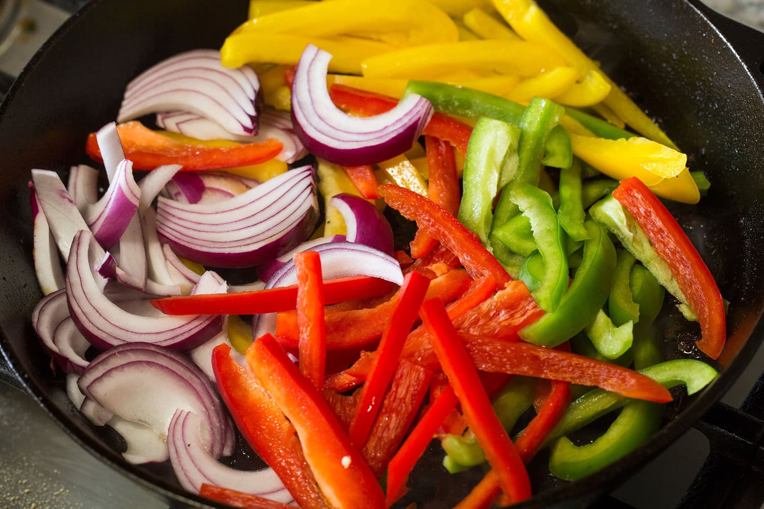 Chicken Fajitas Sliced bell peppers and onions shown in skillet before cooking.