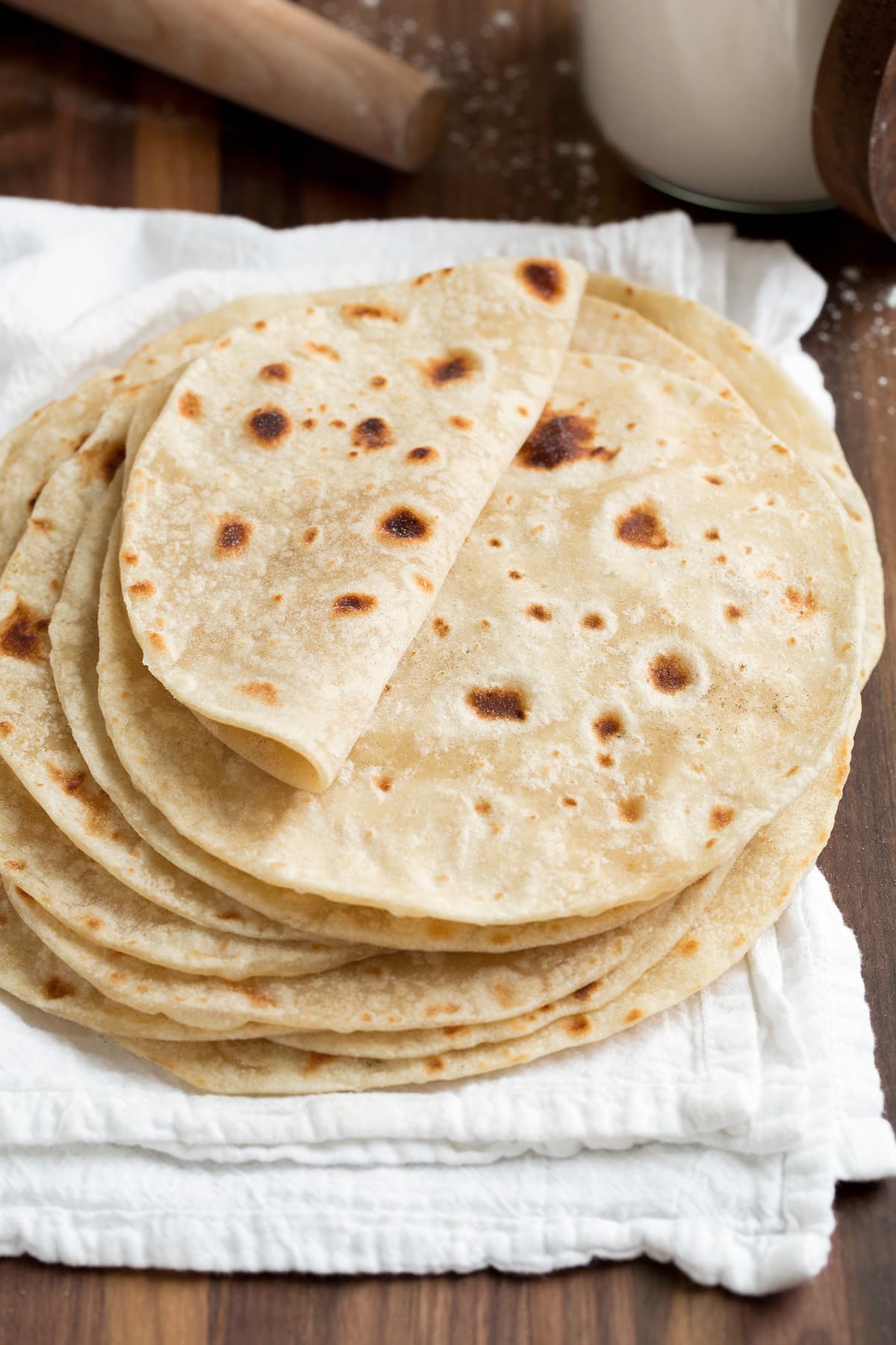 Homemade Flour Tortillas Stack of homemade flour tortillas on a white kitchen cloth. Top tortilla is folded over to show soft and moist texture.