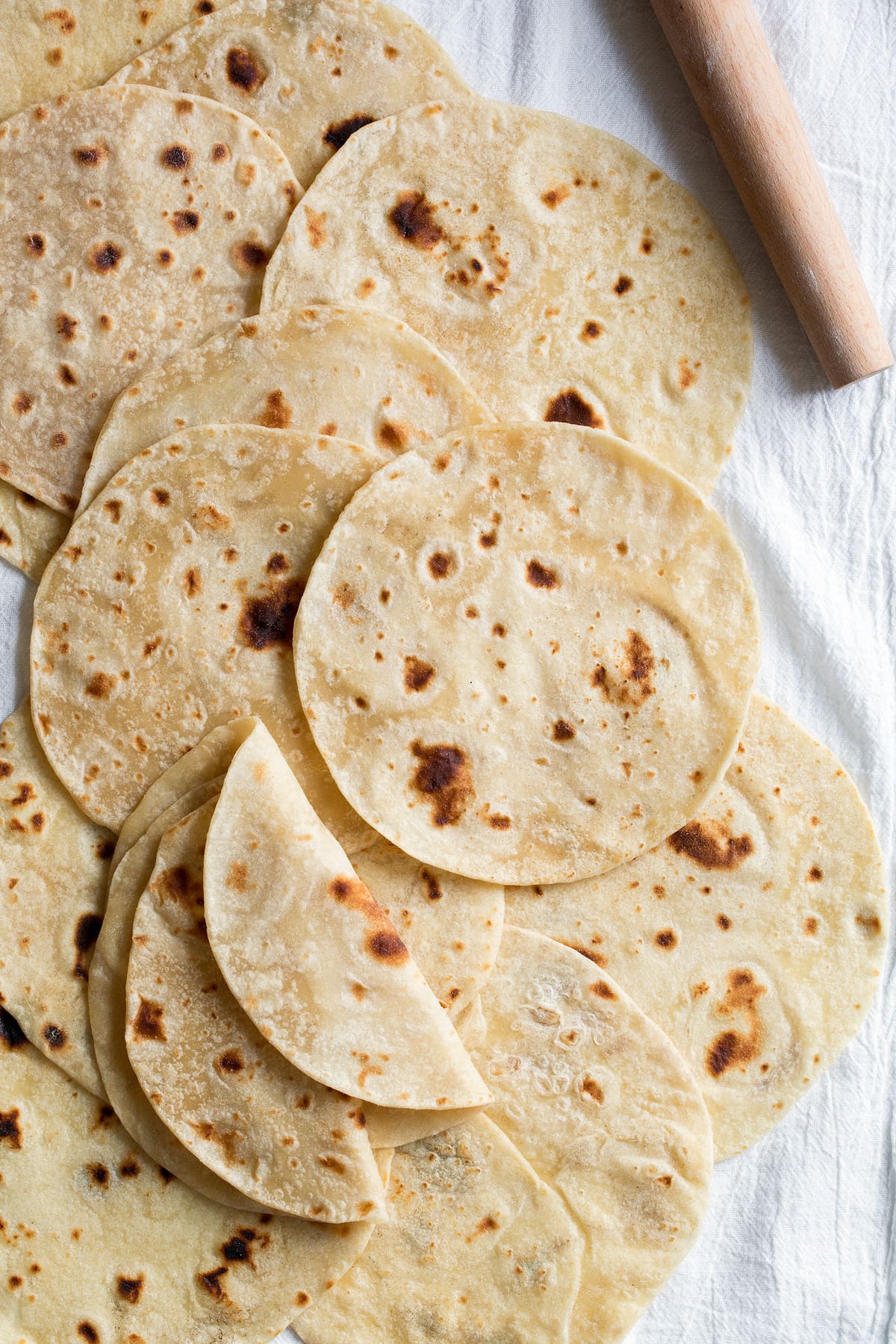 Homemade Flour Tortillas Overhead image of flour tortillas layered across each other on a white kitchen cloth.