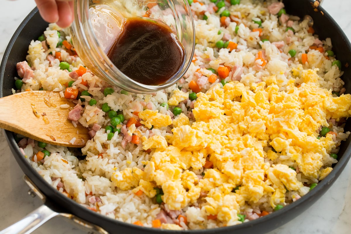 Fried Rice Scrambled eggs added to fried rice mixture in pan.