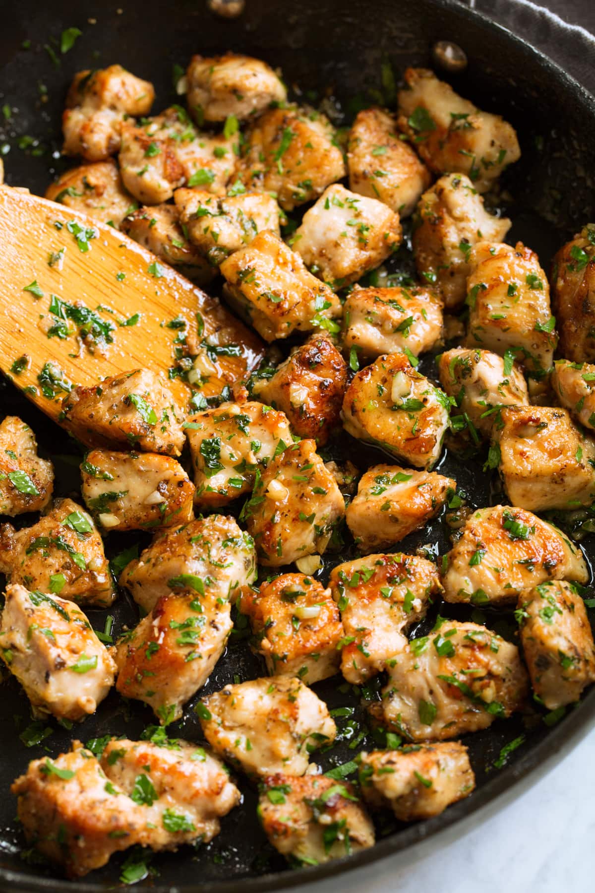Chicken bites in a skillet with garlic and butter sauce.