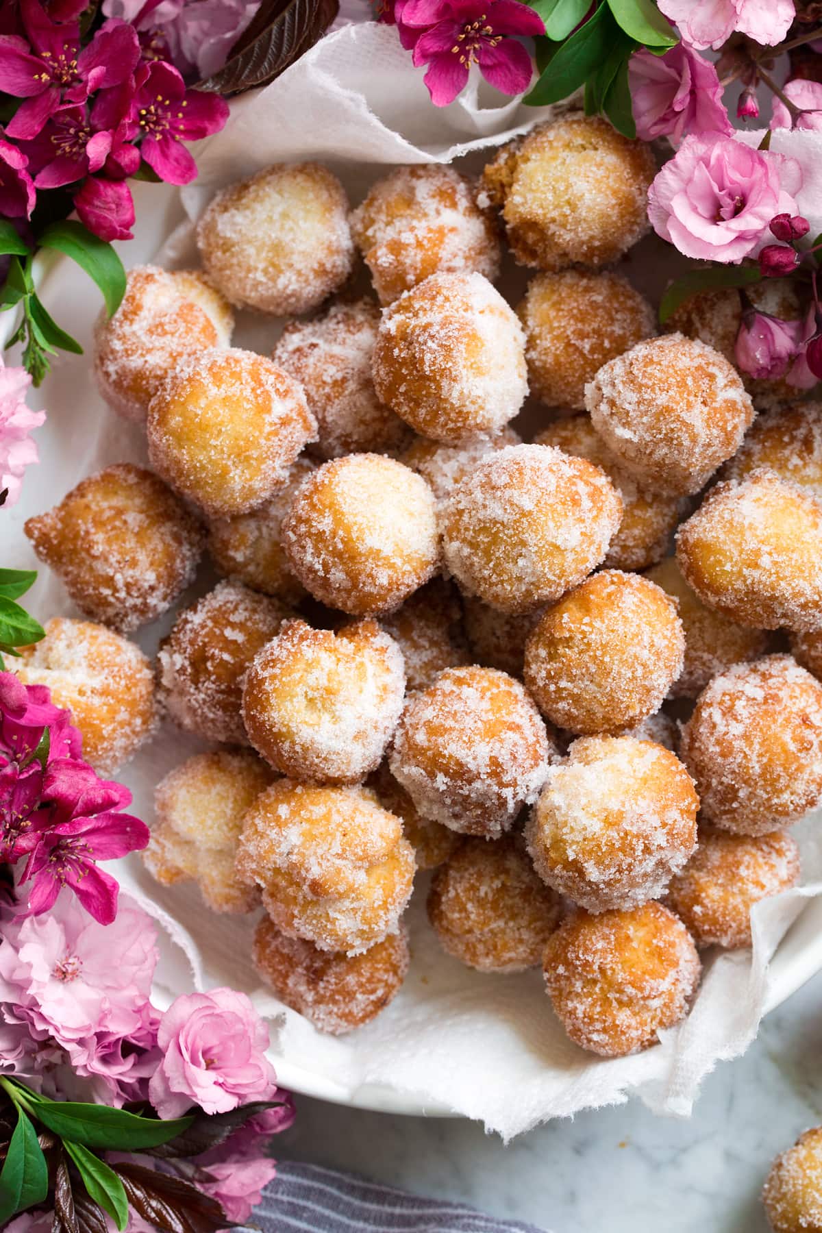 Bowl full of fresh donut holes covered in cinnamon sugar.