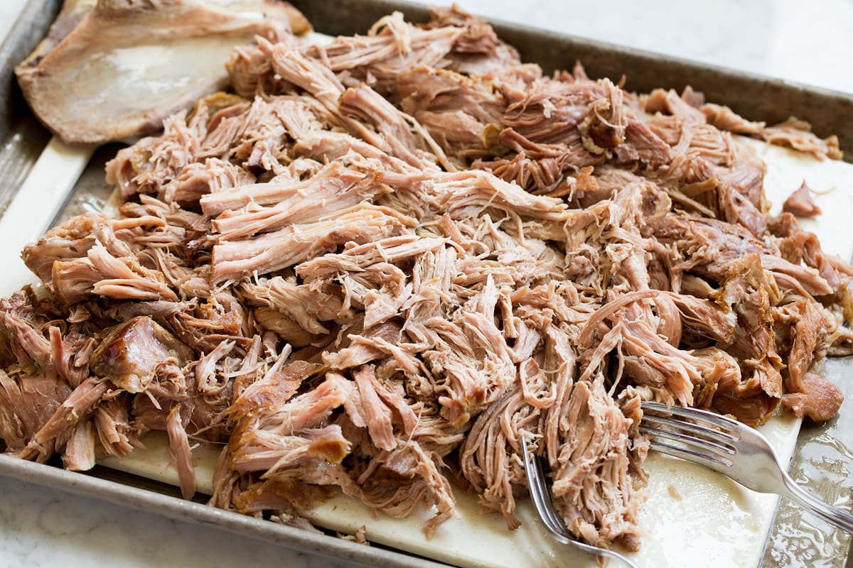 Kalua Pork Kalau pork shredded on a cutting board with two forks to the side.