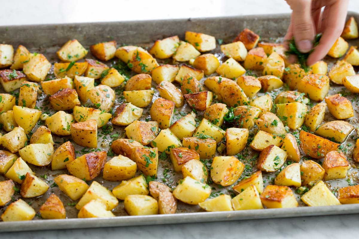 Lemon Roasted Potatoes Hand sprinkling roasted potatoes with parsley.