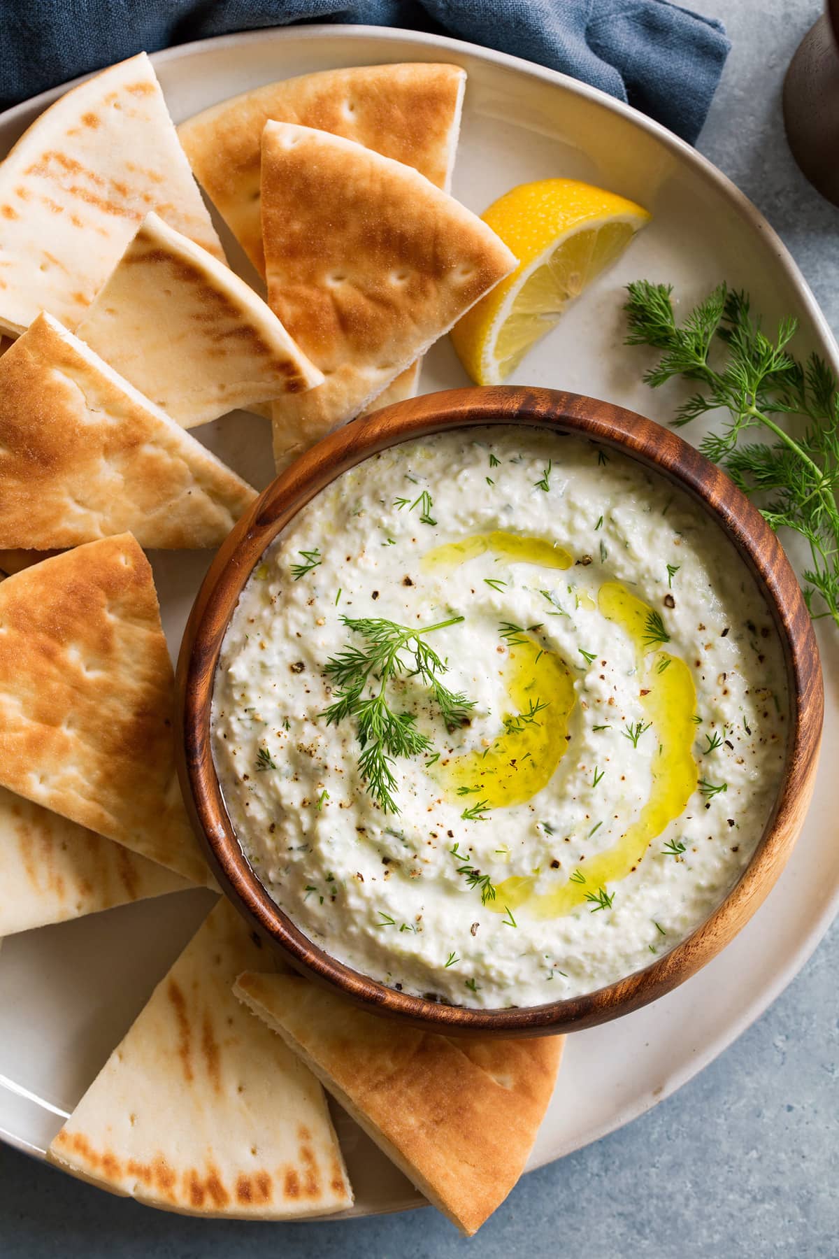 Homemade Tzatziki Sauce Overhead image of tzatziki sauce in a wooden bowl on a white plate with pita bread for dipping.