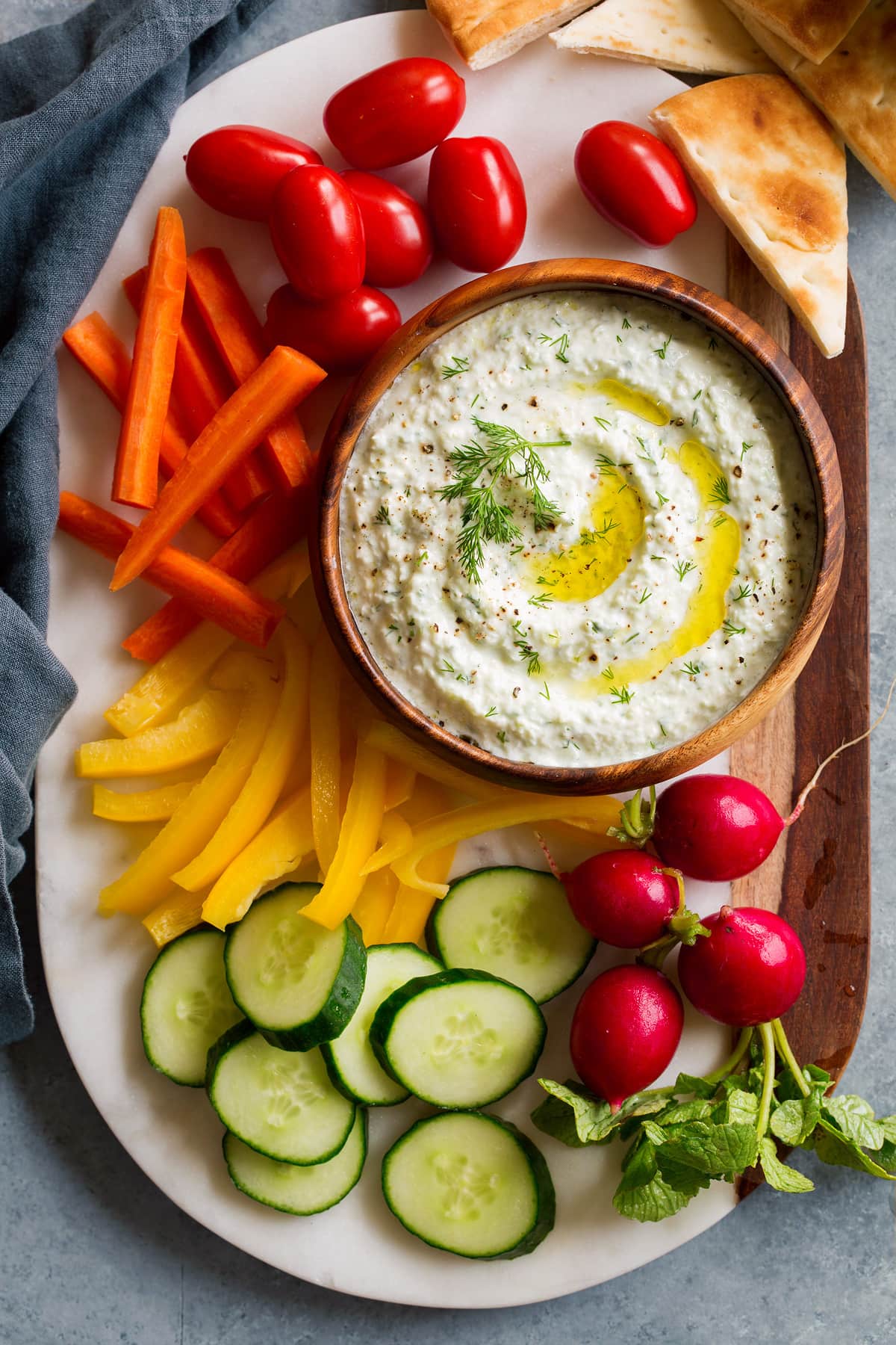 Homemade Tzatziki Sauce Overhead image of tzatziki sauce dip on a marble platter with fresh vegetables around it.