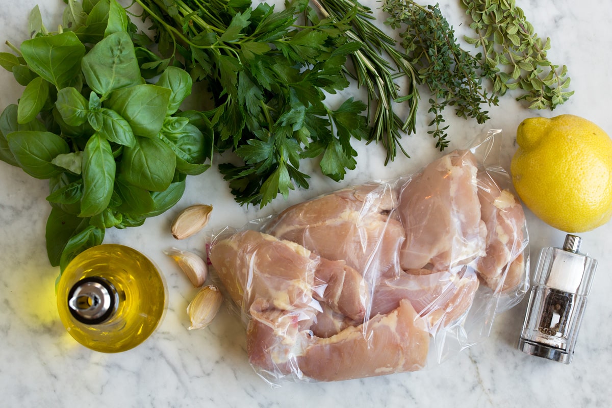 Garlic Herb Grilled Chicken Image of ingredients used to make garlic herb grilled chicken and marinade. Includes olive oil, fresh basil, parsley, rosemary, thyme, oregano, garlic, lemon, salt and pepper.