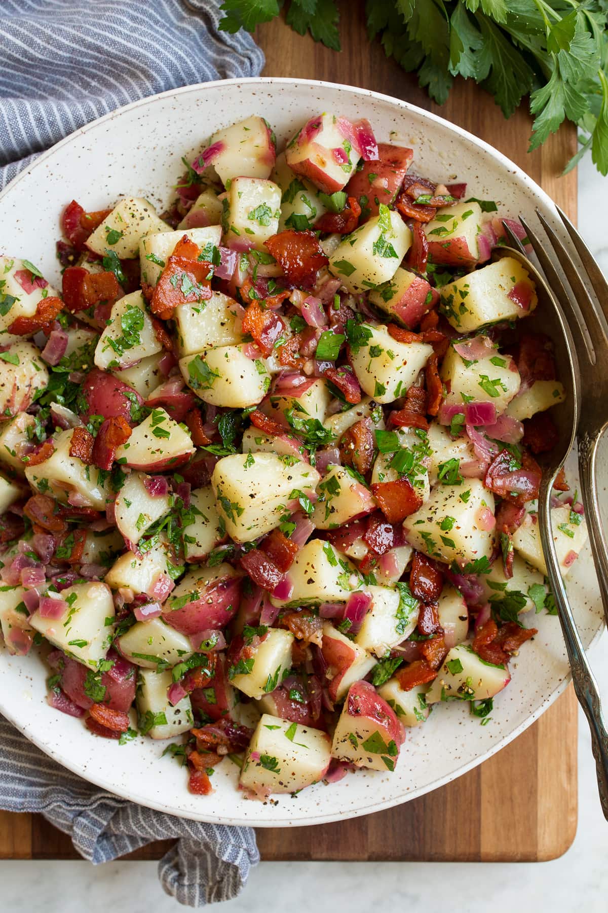 German Potato Salad Overhead image of german potato salad in a bowl with a grey striped napkin to the side.