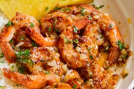 Close up image of Hawaiian garlic shrimp served over white rice with slices of fresh pineapple.
