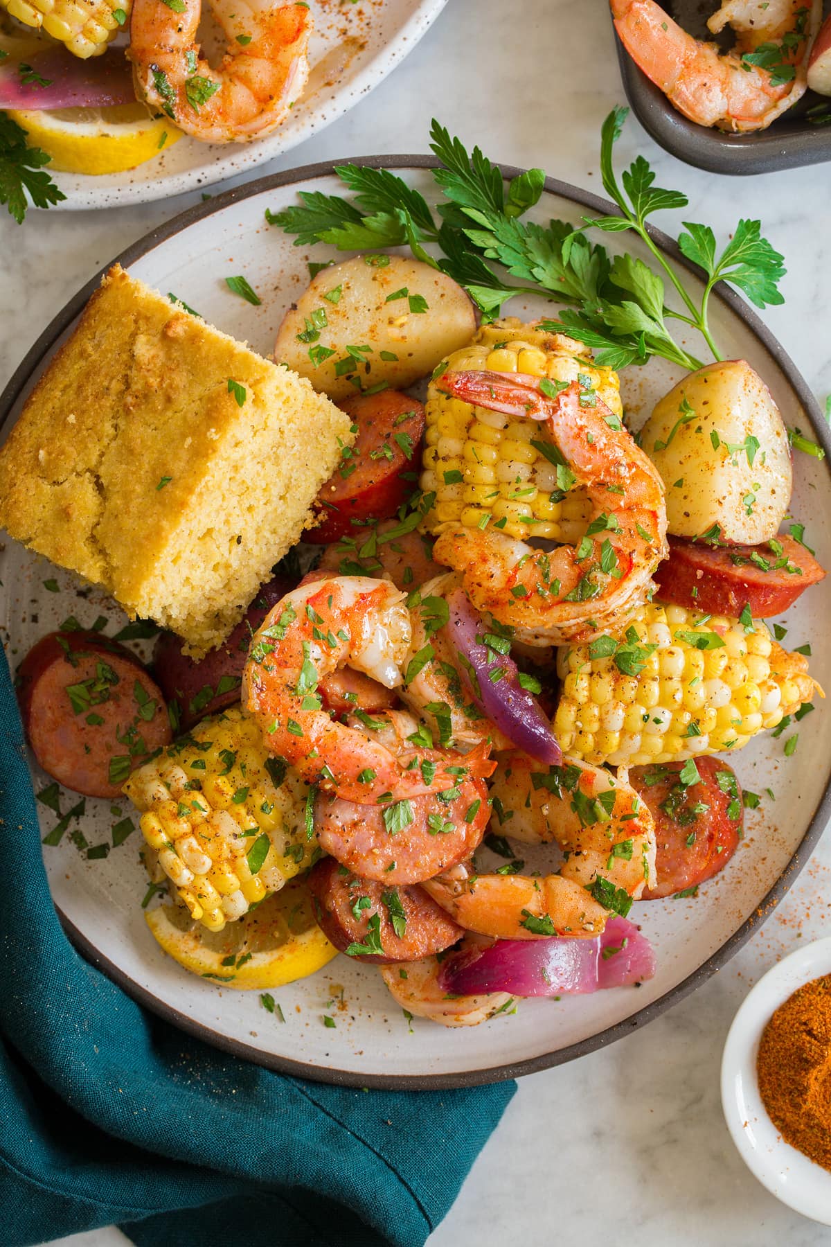 Shrimp Boil Image showing single serving of shrimp boil on a white plate with a serving suggestion of a side of cornbread.