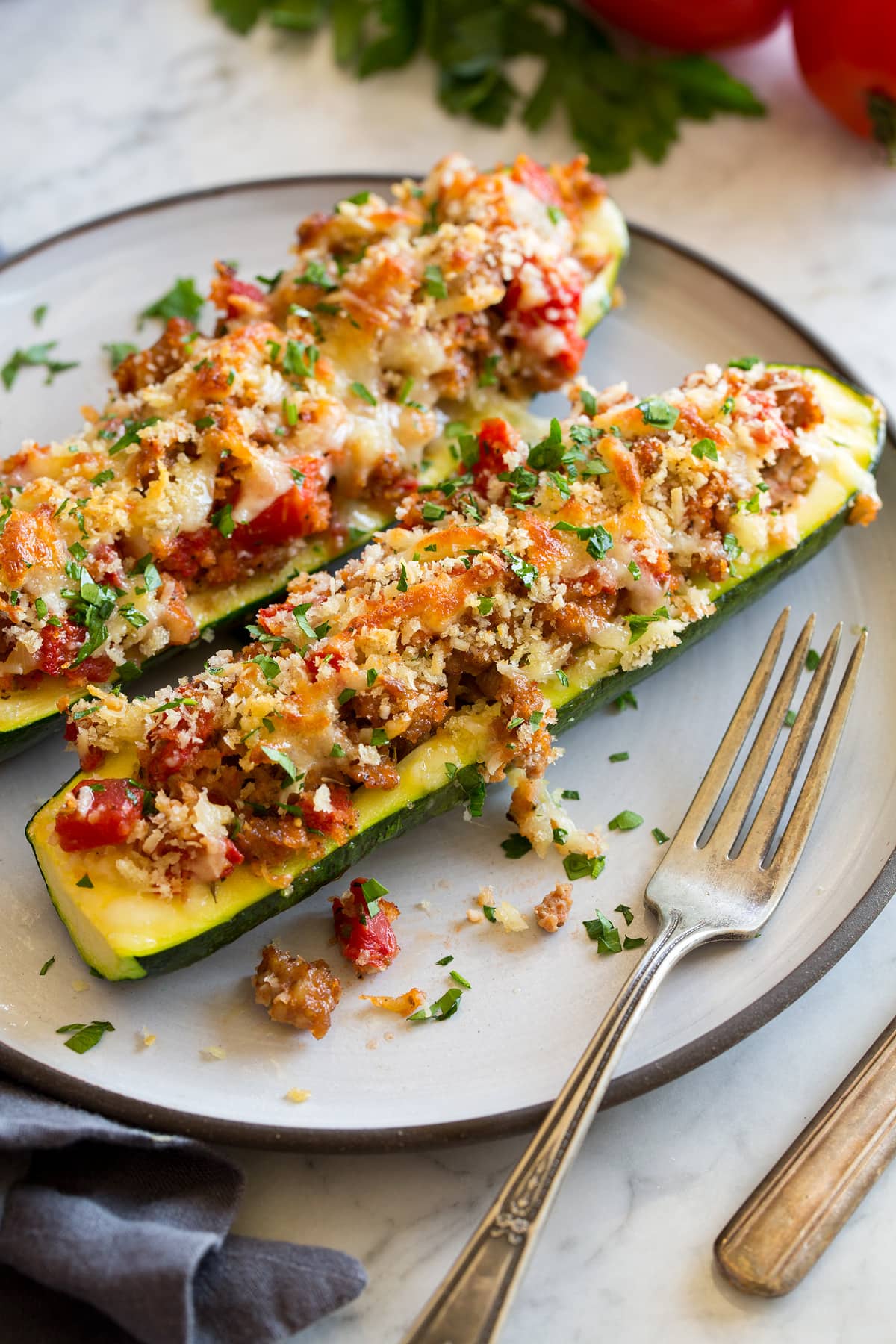 Zucchini Boats Two stuffed zucchini boats on a white dinner plate with a fork to the side.