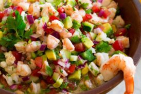 Ceviche in a wooden dip bowl with tortilla chips on the side.