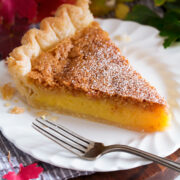 Slice of chess pie on a white dessert plate with fall leaves surrounding plate.