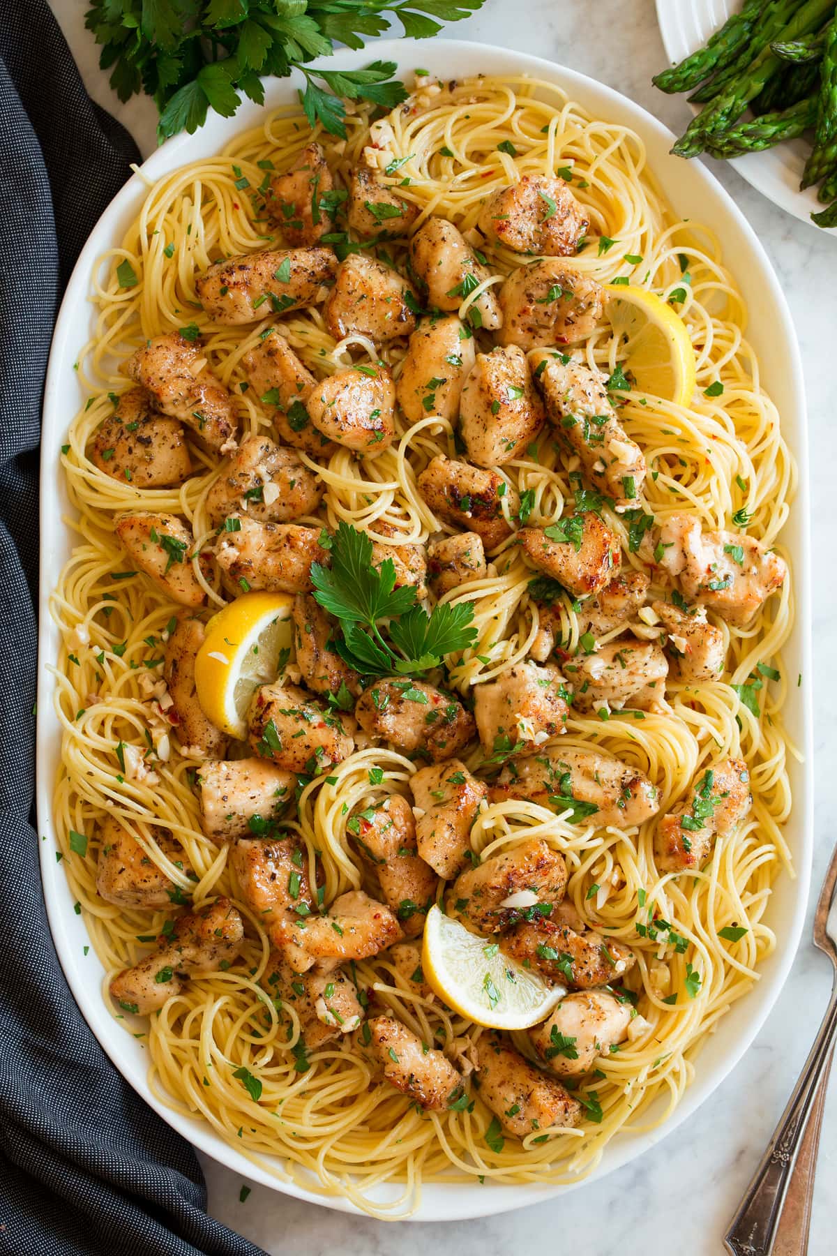 Chicken Scampi Chicken scampi shown on an oval serving platter. Includes thin spaghetti, lemon, browned chicken pieces and parsley.