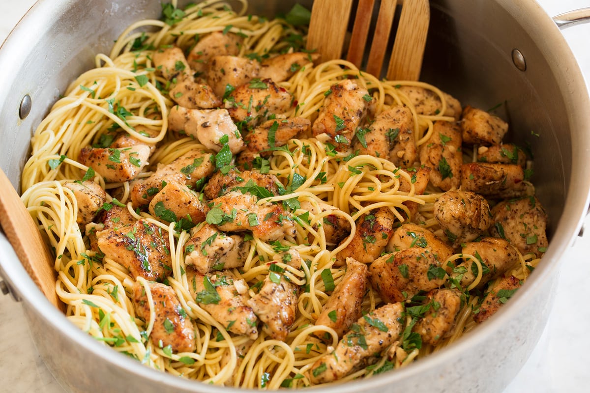 Chicken Scampi Pasta and chicken scampi pieces being tossed together in a pot.